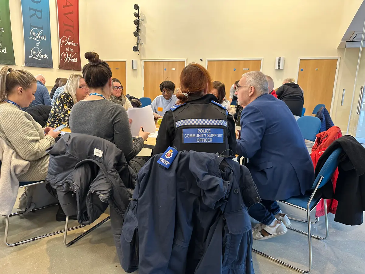 A group of local residents meeting around a table, the group including a police community officer