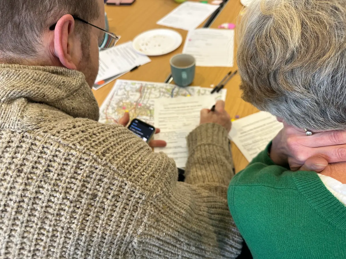 Two elderly residents writing notes at a meeting